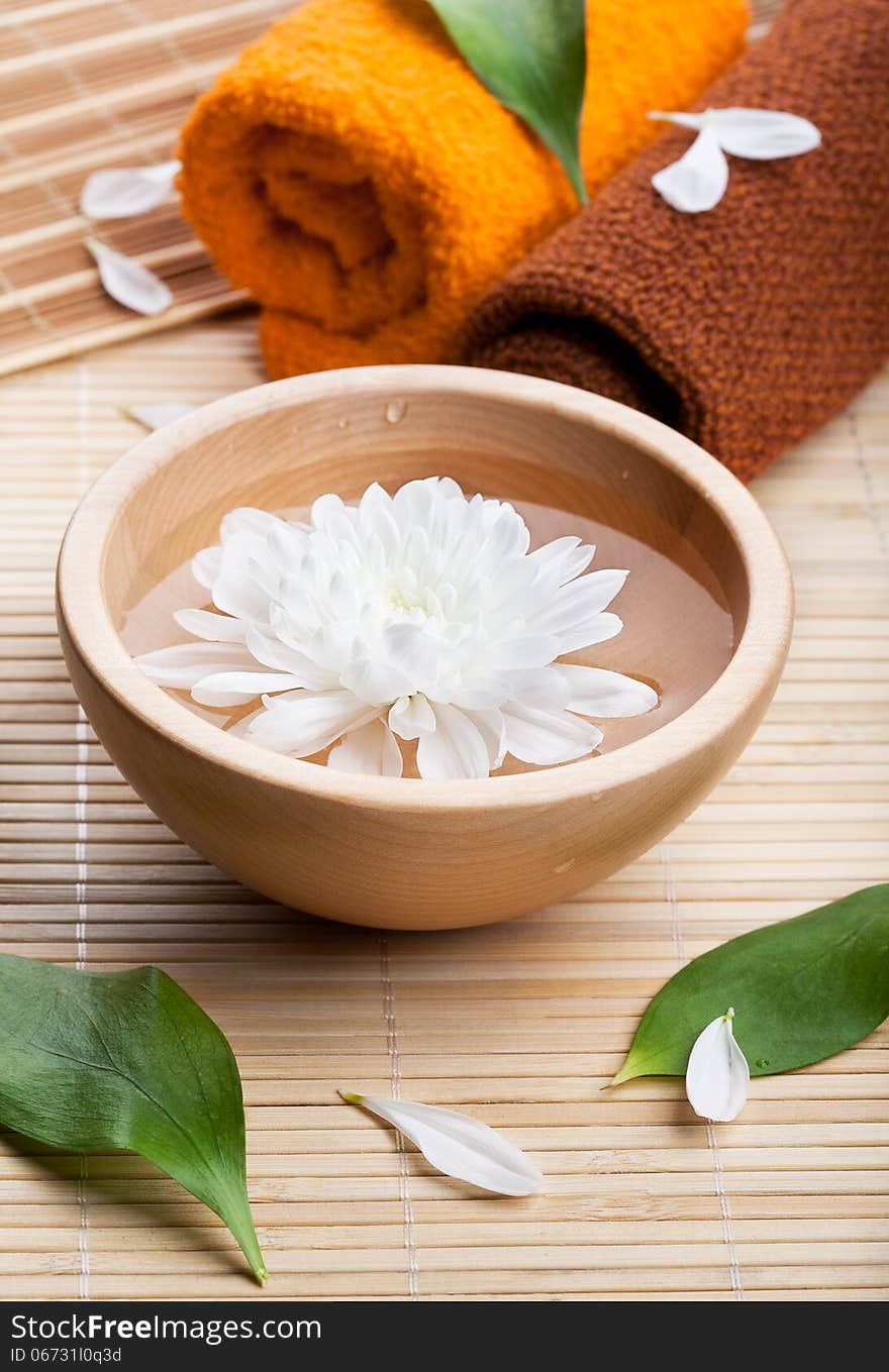 Towels and white daisy in wooden bowl. Spa and body care. Towels and white daisy in wooden bowl. Spa and body care