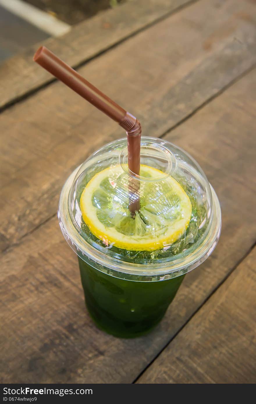 Iced green tea on the wooden table in the garden of coffee shop.