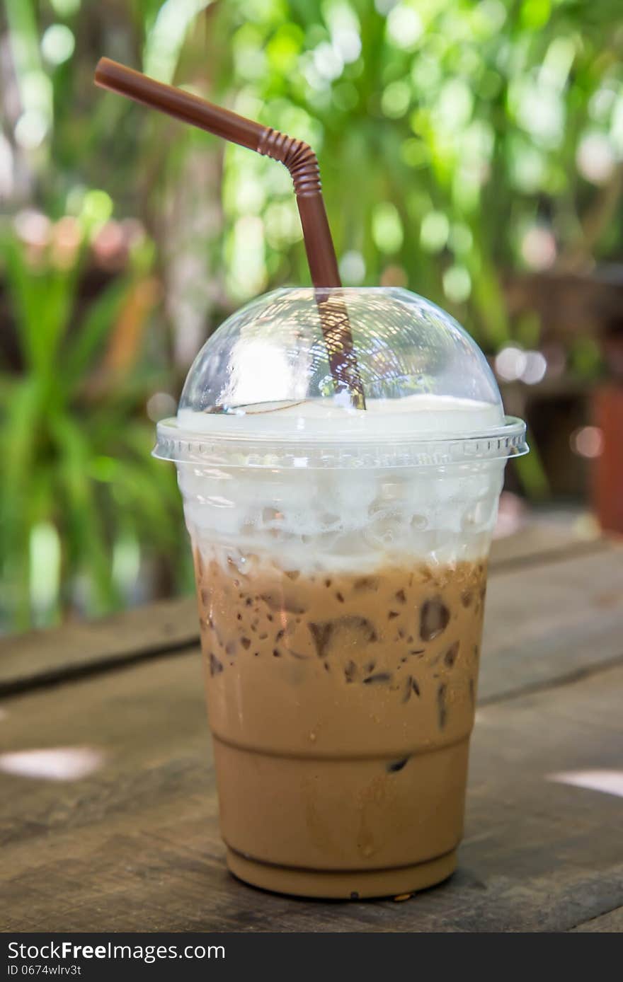 Iced coffee on the wooden table in the garden of coffee shop.