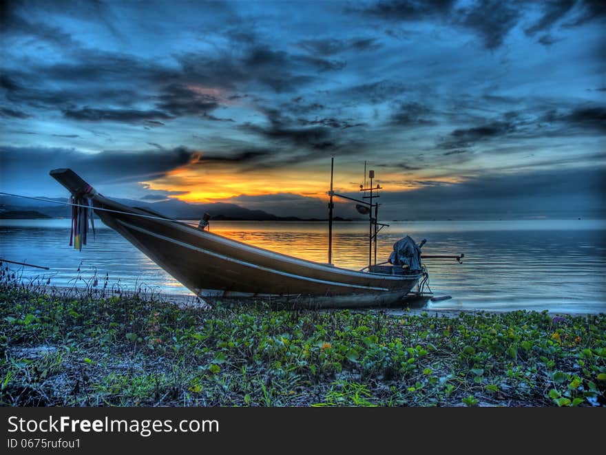 A long tail boat is laying ashore waiting to being used again to catch the fish on the sea. A long tail boat is laying ashore waiting to being used again to catch the fish on the sea.