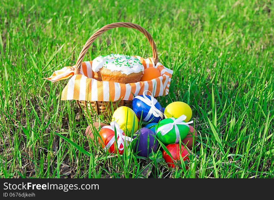 Easter cake on a striped napkin in a basket and eggs on green spring grass. Easter cake on a striped napkin in a basket and eggs on green spring grass