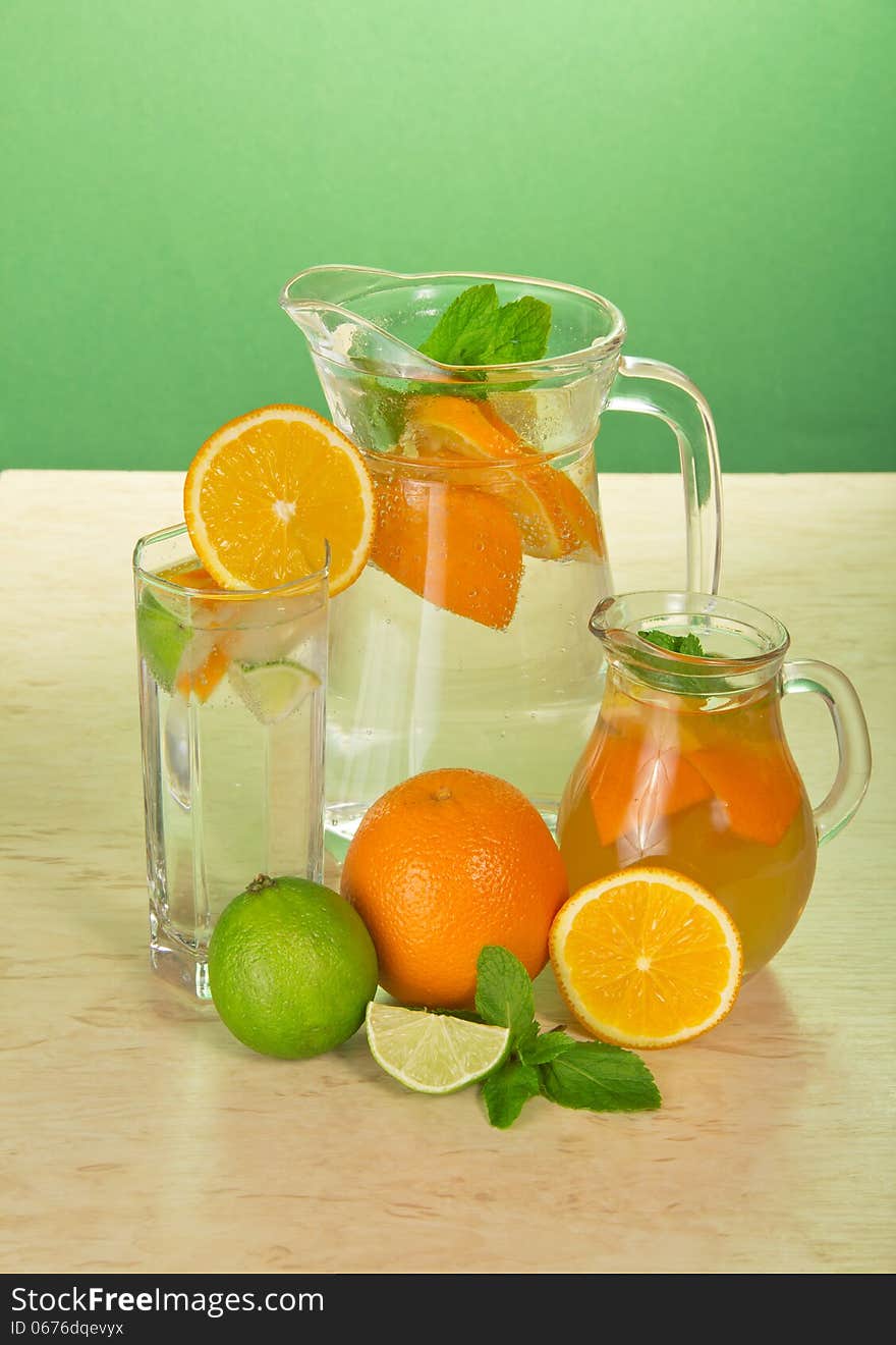 Juice with drinks, a glass, a juicy lime and oranges on a table. Juice with drinks, a glass, a juicy lime and oranges on a table