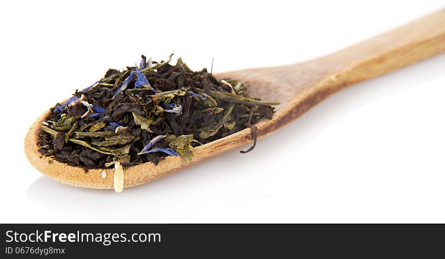 Fragrant dry tea leaves with cornflowers in the wooden spoon, on white