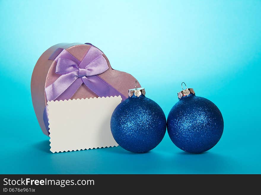 Original gift box heart, Christmas spheres and blank card on a blue background