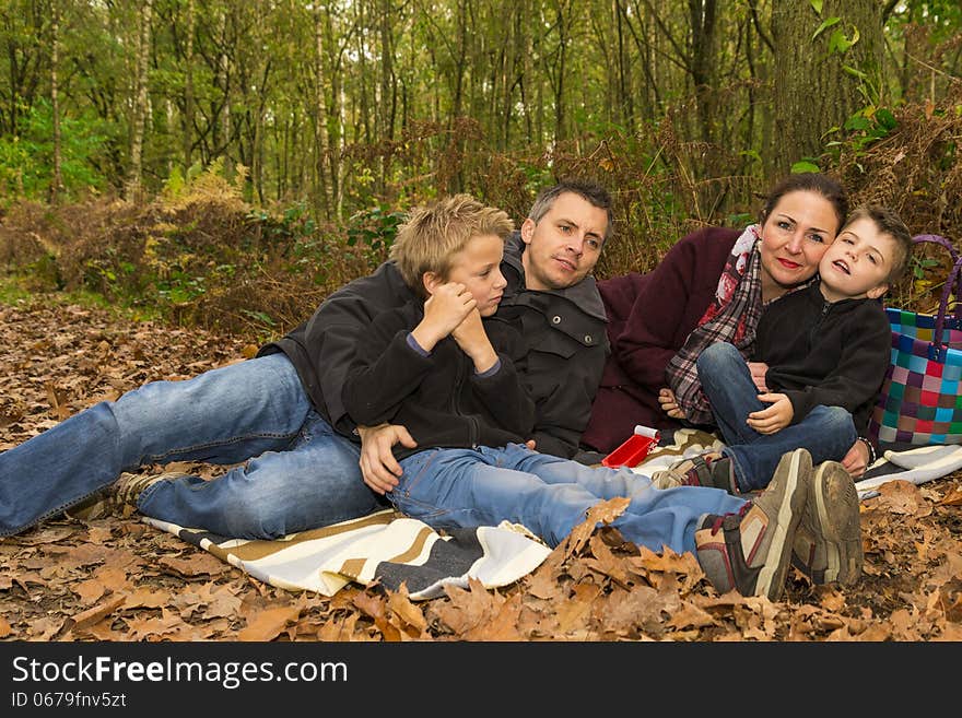 Happy family relaxing in a forest, enjoying fall. Happy family relaxing in a forest, enjoying fall