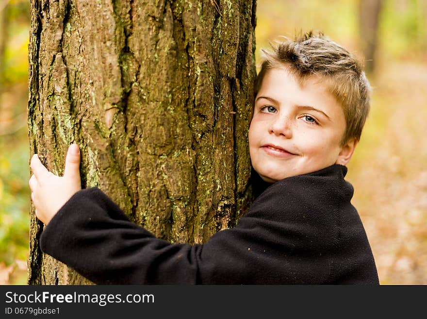 Kid in a forest hugging a tree. Kid in a forest hugging a tree