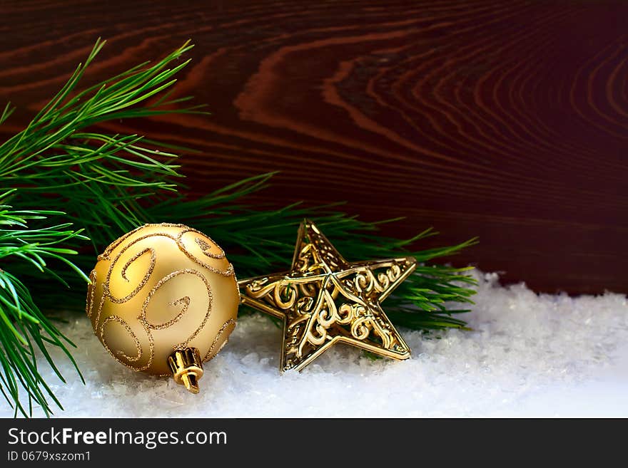 Fir-tree twig decorated with a ball and a star on the wooden background