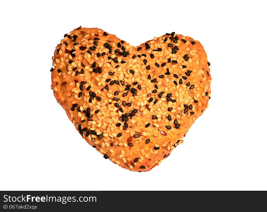 A heart-shaped home-made bread topped with black and white sesame seeds, on a white background. A heart-shaped home-made bread topped with black and white sesame seeds, on a white background