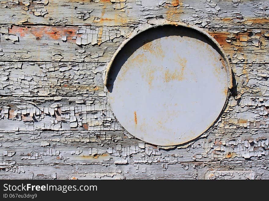 Old iron porthole on wooden