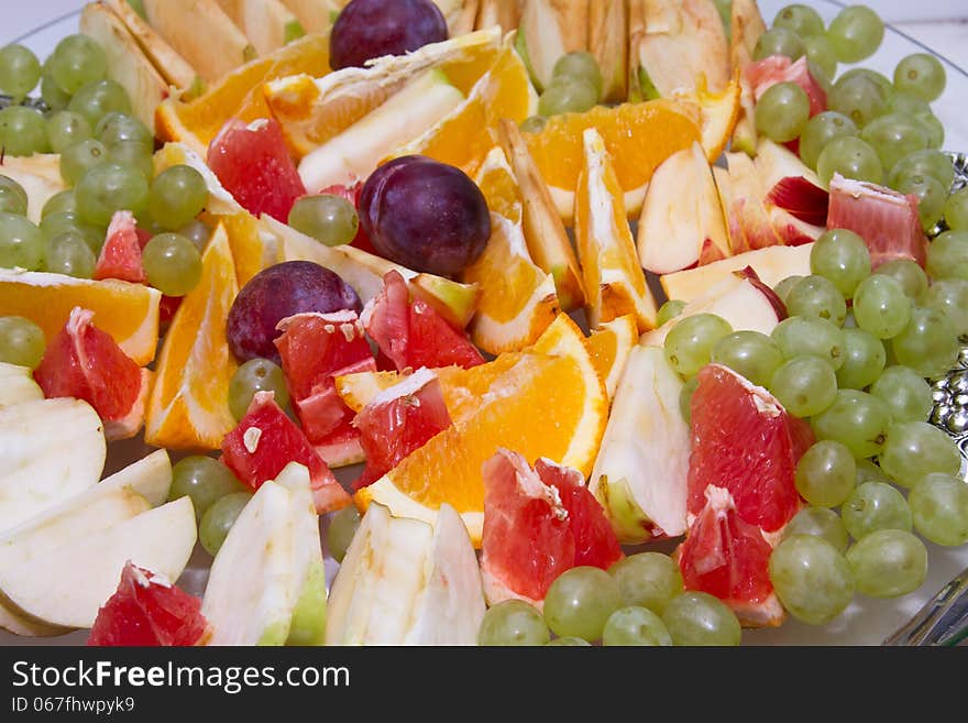 Dish with sliced oranges, grapefruit, Apple and grapes. Dish with sliced oranges, grapefruit, Apple and grapes