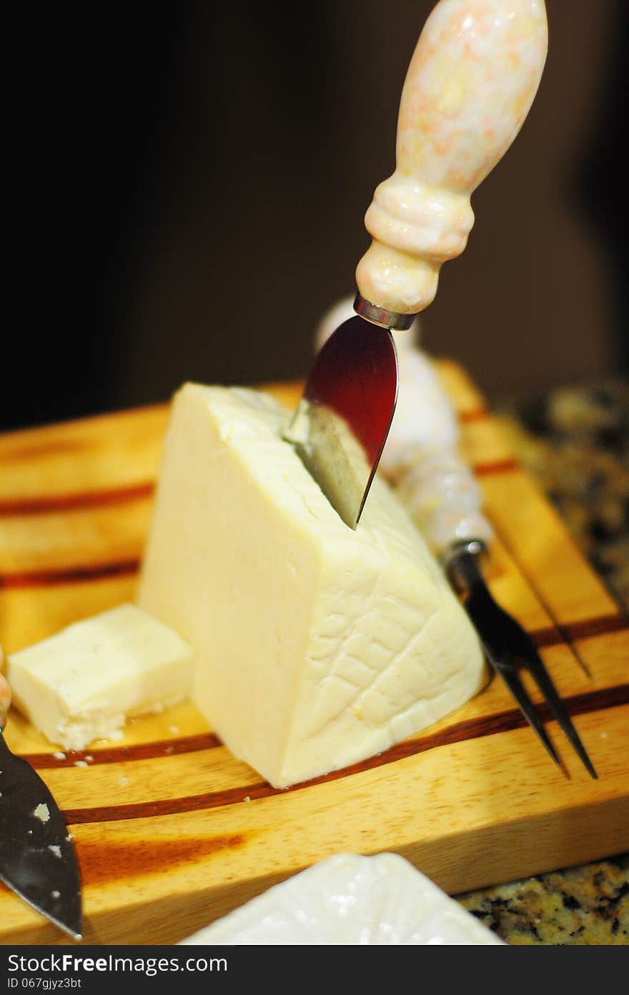 Chunk of sharp white cheese with a cheese knife ready to be served. Chunk of sharp white cheese with a cheese knife ready to be served.