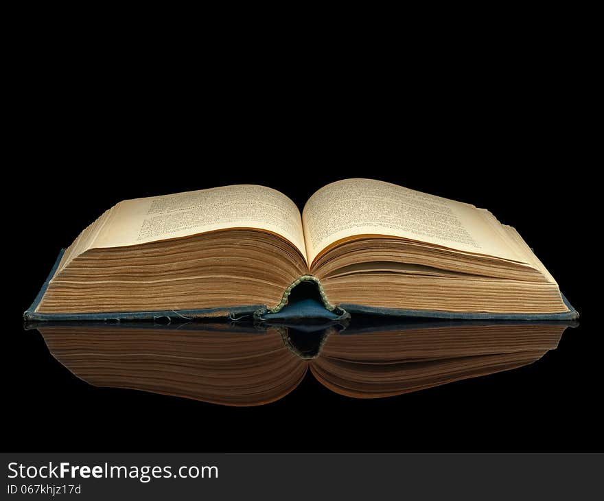 The old opened book in dark blue cover on a black background. The old opened book in dark blue cover on a black background