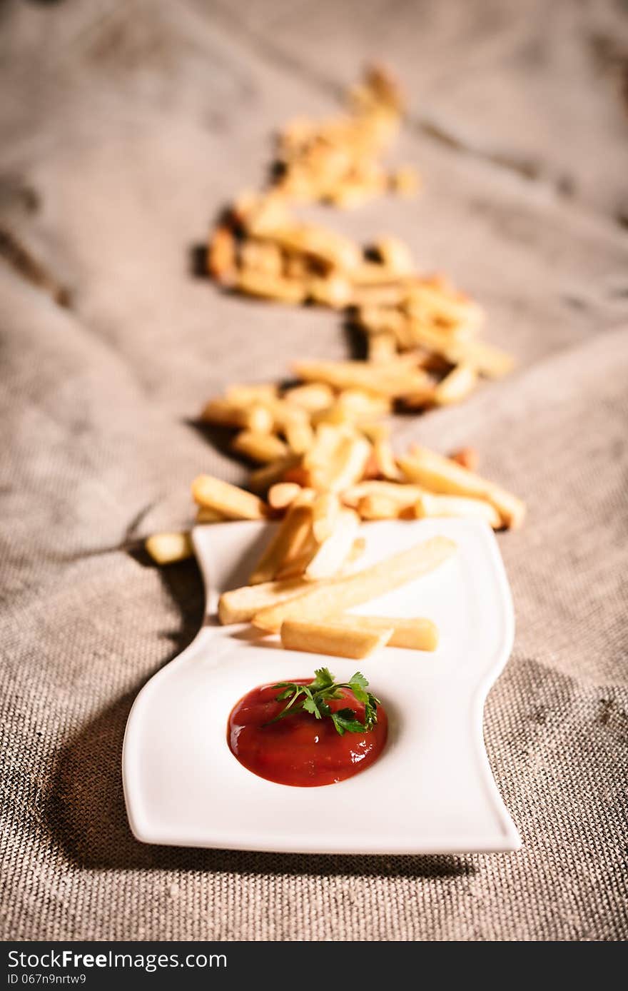 Fried French fries with red sauce ketchup on beautiful plate with linen background. Fried French fries with red sauce ketchup on beautiful plate with linen background