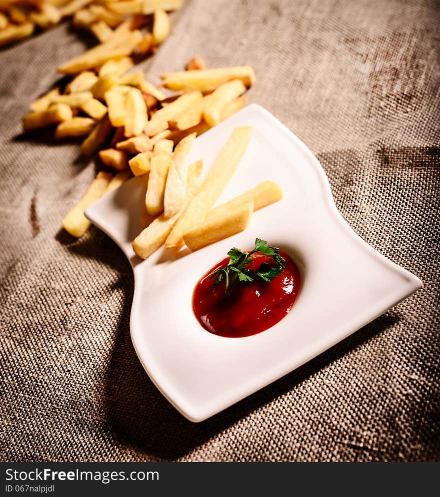 Fried French fries with red sauce ketchup on beautiful plate with linen background. Fried French fries with red sauce ketchup on beautiful plate with linen background