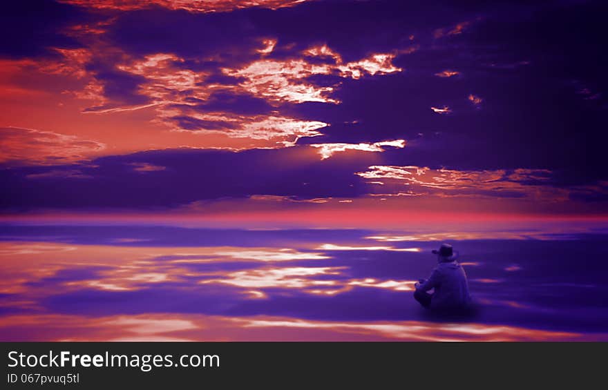 Beautiful sunset sky with clouds reflected in the mirrored surface of the ocean. Pensive cowboy sitting cross-legged and throws small stones. Beautiful sunset sky with clouds reflected in the mirrored surface of the ocean. Pensive cowboy sitting cross-legged and throws small stones