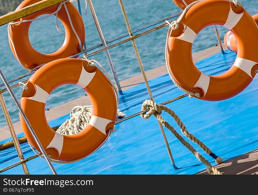 Ship railing and lifebuoy ring. View from the deck of a boat. Sea travel background with lifebuoys. Ship railing and lifebuoy ring. View from the deck of a boat. Sea travel background with lifebuoys.