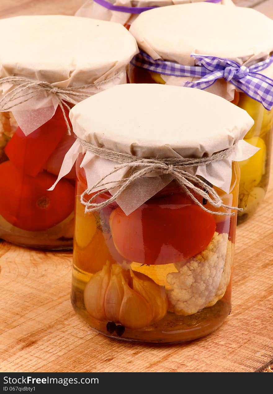 Arrangement of Mixed Pickled Vegetables in Glass Jars Covered with Butter-paper closeup on Wooden background