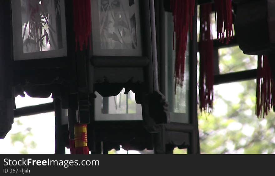 Decorative lanterns, carved from dark wood with painted windows and red tassels with gold braid, swaying in the wind