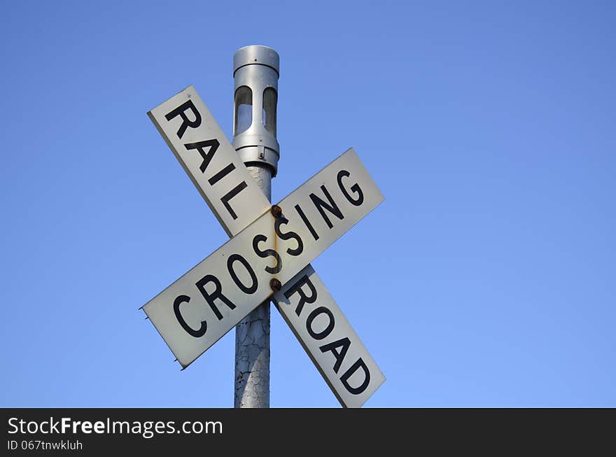 Railroad crossing sign against a clear blue summer sky