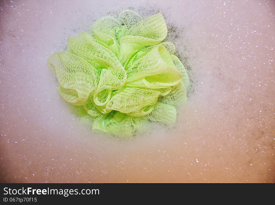 A lime green loofah in a bubble bath. A lime green loofah in a bubble bath