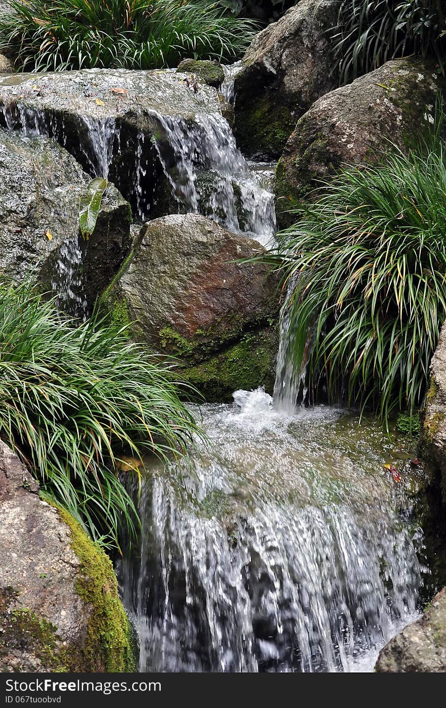 Cascade of water stream with mossy rocks and plants