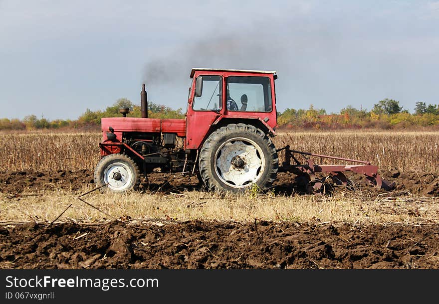 Red old tractor ploughing field. Red old tractor ploughing field