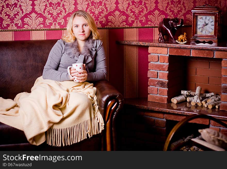 Nice woman with cup of hot tea sits on the sofa