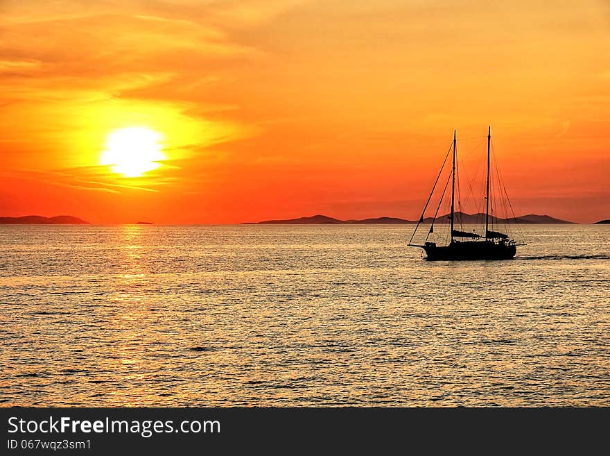 Sunset above the calm sea with sailboat