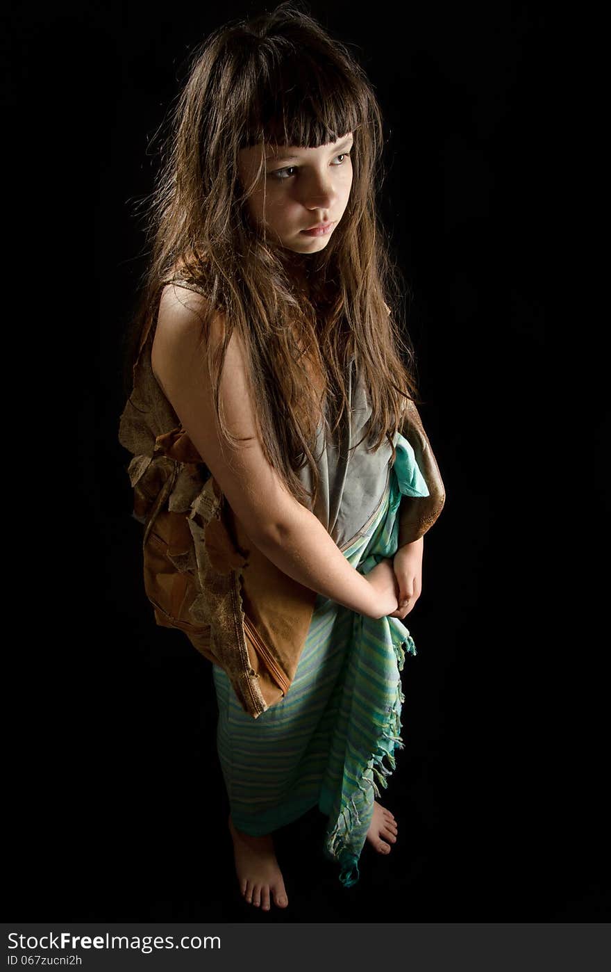 Girl in rags, barefoot on black background