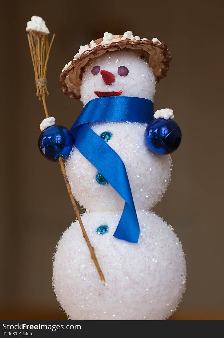 Closeup of toy snowman wearing a straw hat and scarf, holding broom. Closeup of toy snowman wearing a straw hat and scarf, holding broom