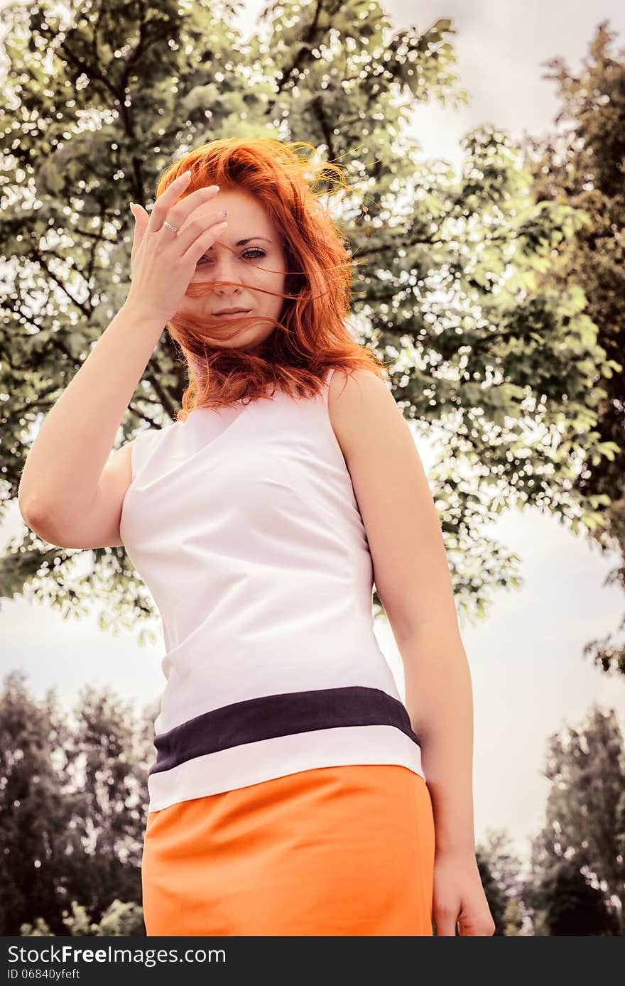 Beautiful free woman with red hair has rest in park