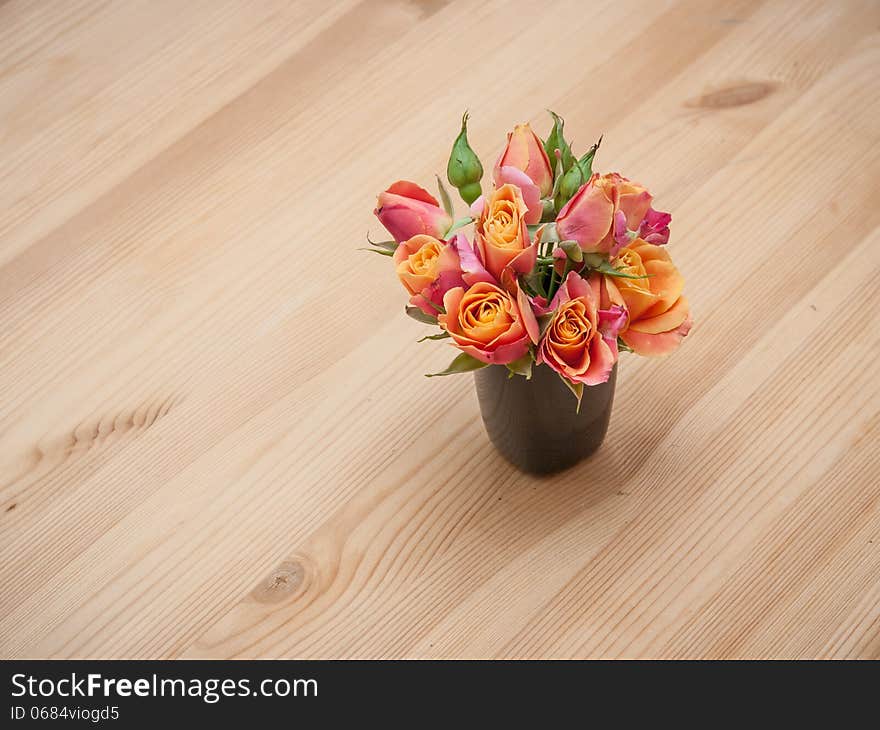 Simple arrangement from orange roses on wooden background