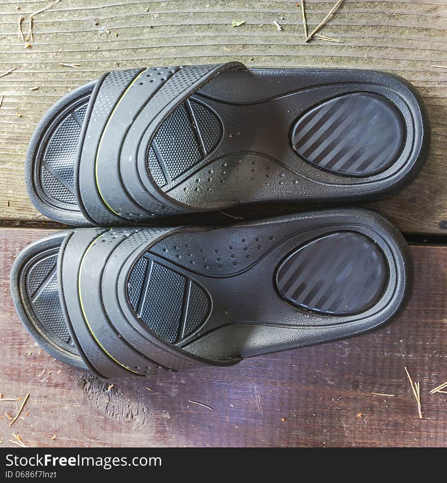 Black rubber flip-flops on the wooden terrace