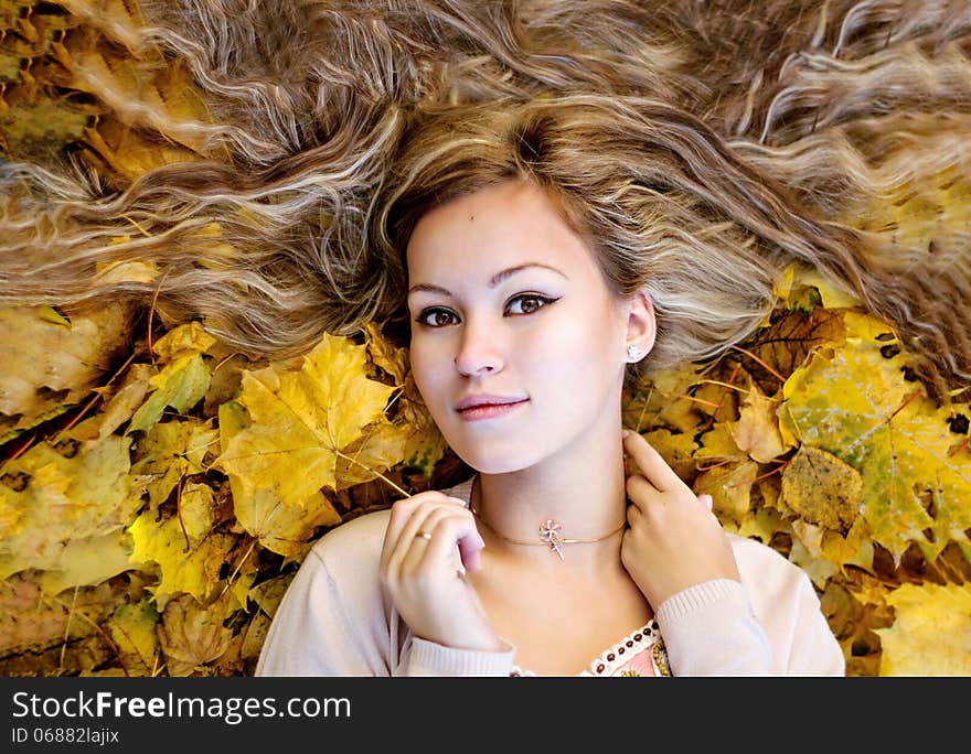 Beautiful woman lying with autumn leaves