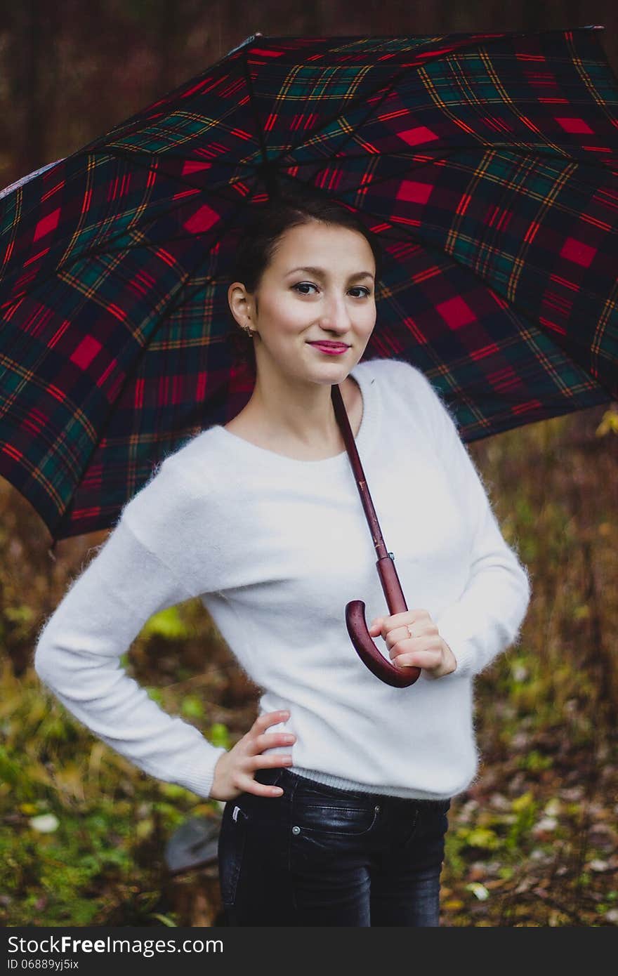 Girl in white sweater smiling with umbrella