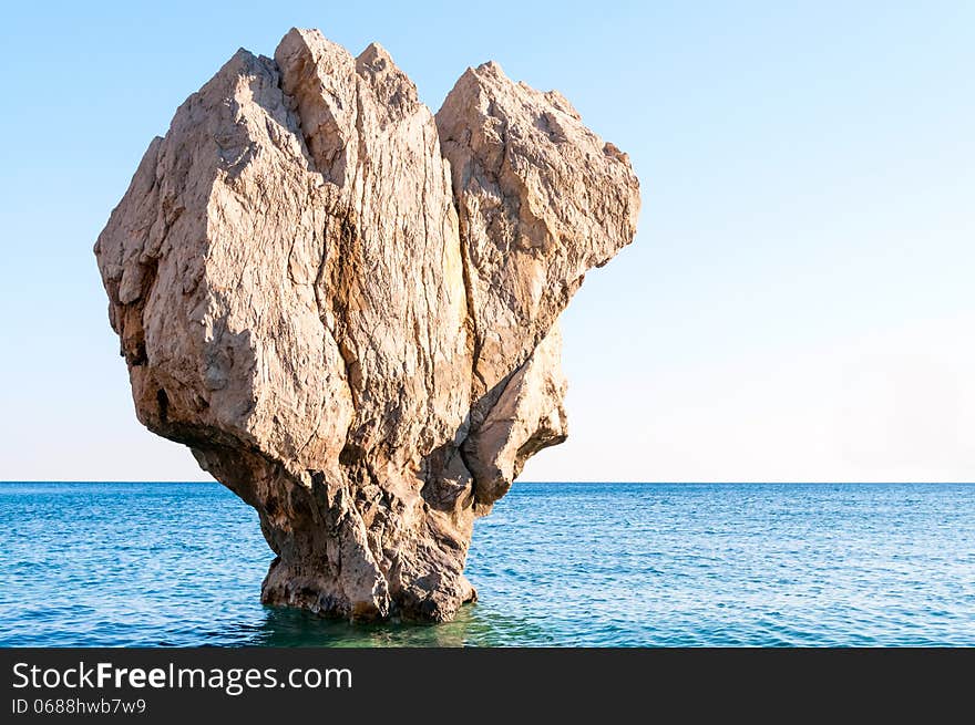 Huge rock sticking out of the water on the beach. Huge rock sticking out of the water on the beach