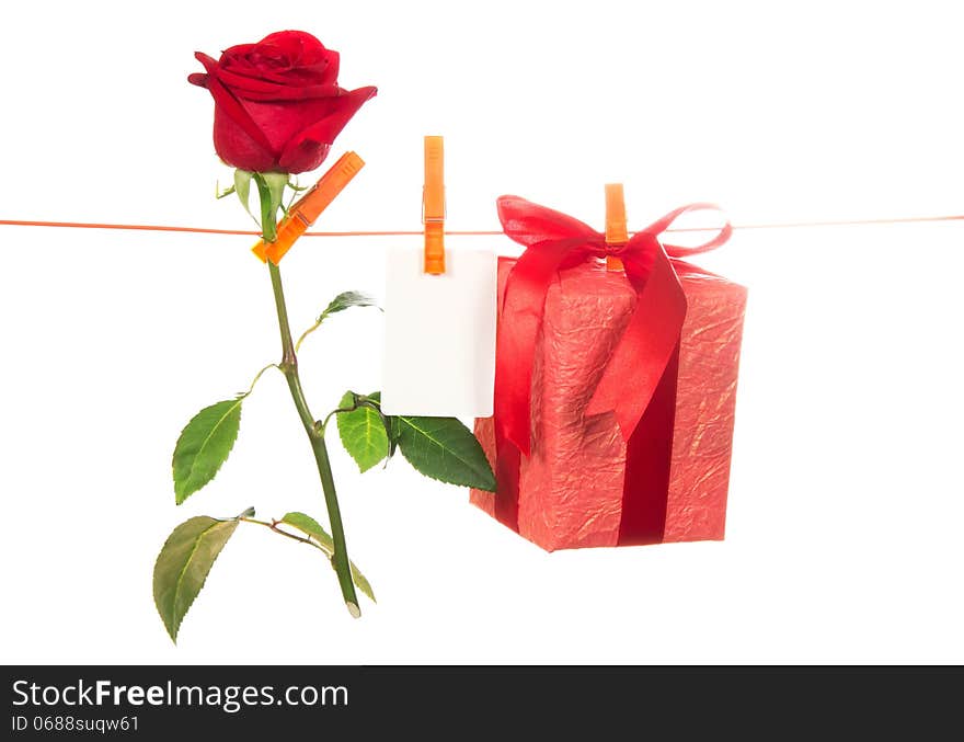 The rose, card and gift hang on a linen rope isolated on the white