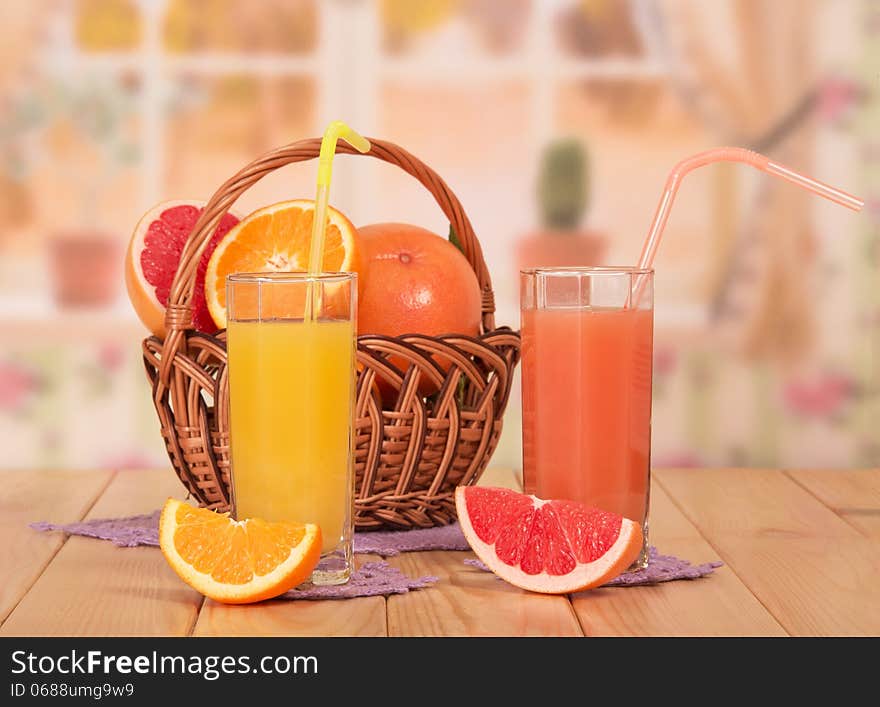 Orange and grapefruit juice in glasses on kitchen background