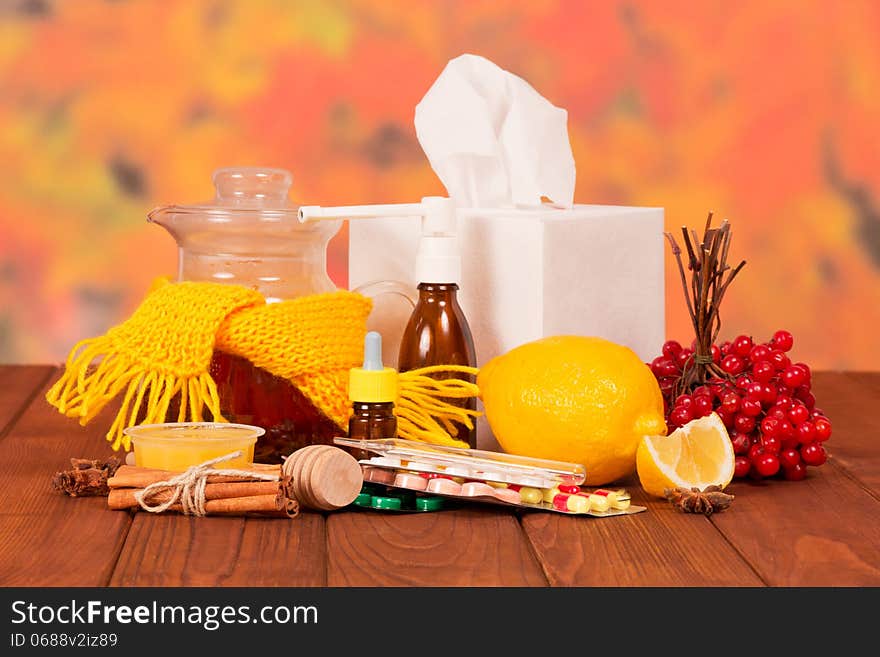 Various cold medicines on a table against autumn foliage