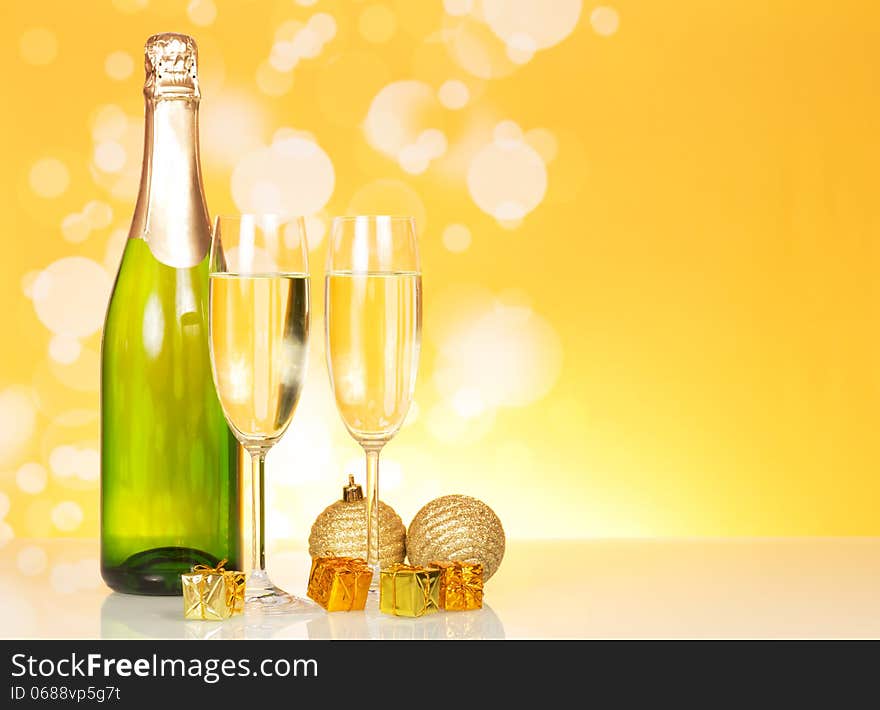 Bottle of champagne and two glasses on an abstract yellow background