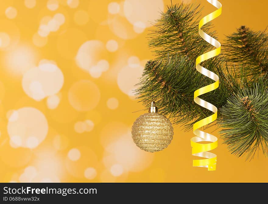 Branch of a New Year tree on an abstract yellow background. Branch of a New Year tree on an abstract yellow background