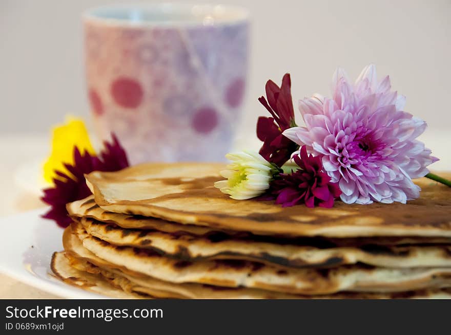 Flowers on pancakes with a cup of tea in the background