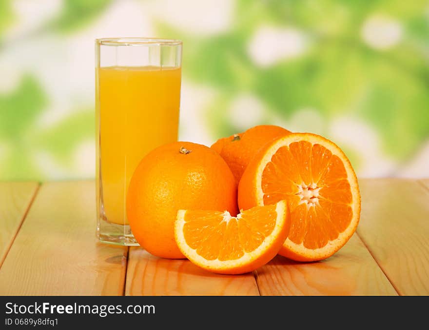 Orange juice on a wooden table against green foliage