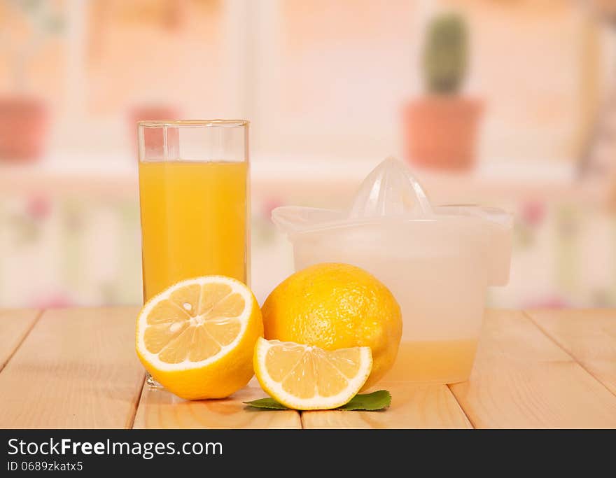 The cut lemon, juice extractor and glass of lemon juice against kitchen