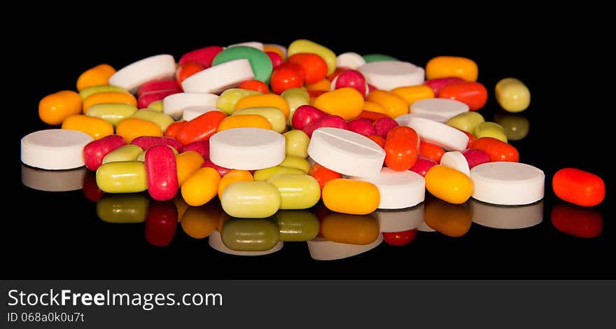 Handful of multi-colored tablets isolated on the black