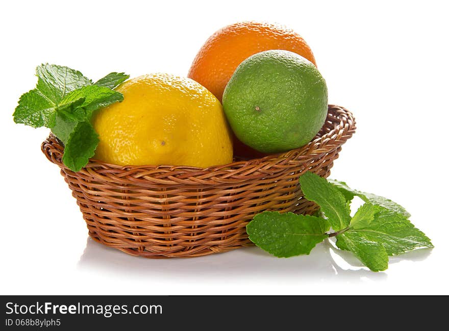 Lemon, lime, orange in a wicker basket, spearmint, isolated on white