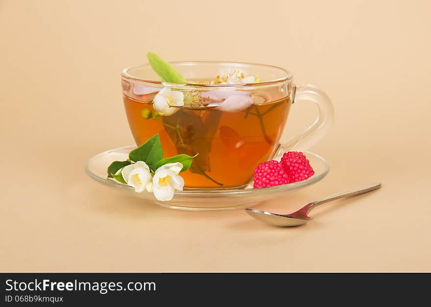 Cup of flower tea a spoon and raspberry on a beige background. Cup of flower tea a spoon and raspberry on a beige background