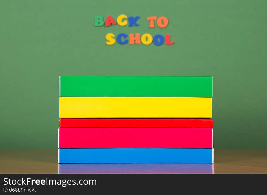 Stack of books and set of plastic letters, on a green background. Stack of books and set of plastic letters, on a green background