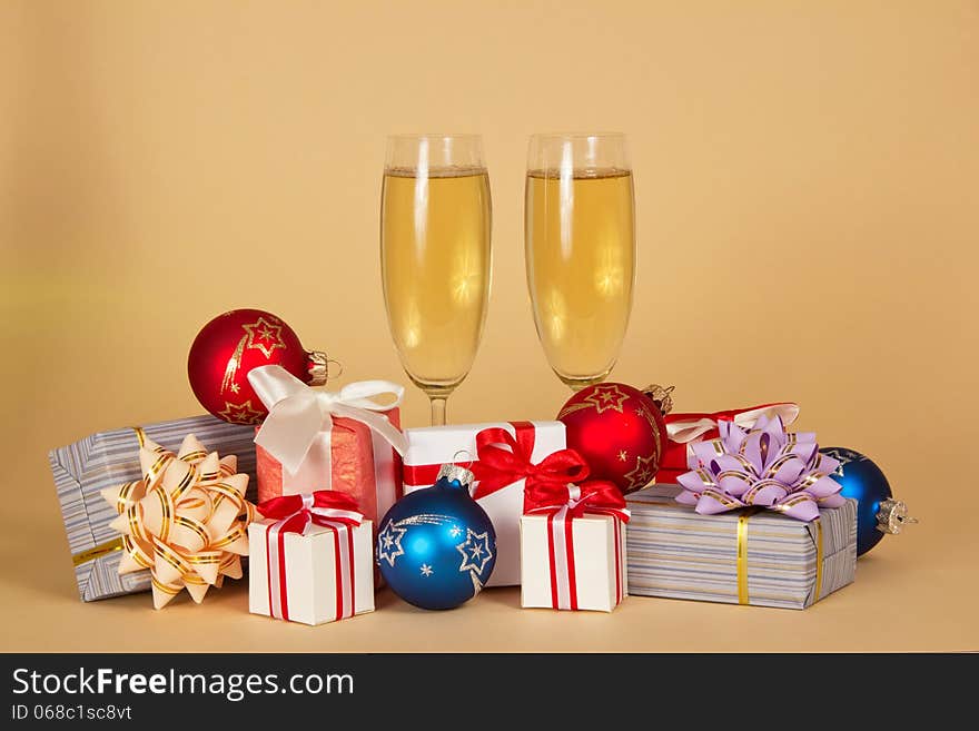 Set of different gift boxes, toys and wine glasses with champagne on a beige background