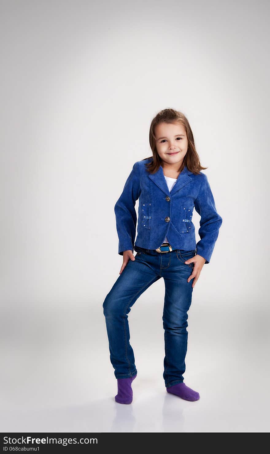 Little girl in blue jeans and jacket posing in the studio